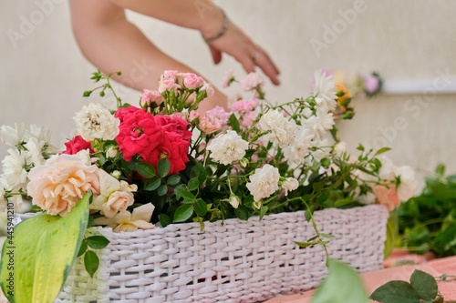 Female florist doing floral arrangement outdoors. Flower basket creation workflow