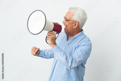 Middle age Brazilian man isolated on white background shouting through a megaphone to announce something in lateral position