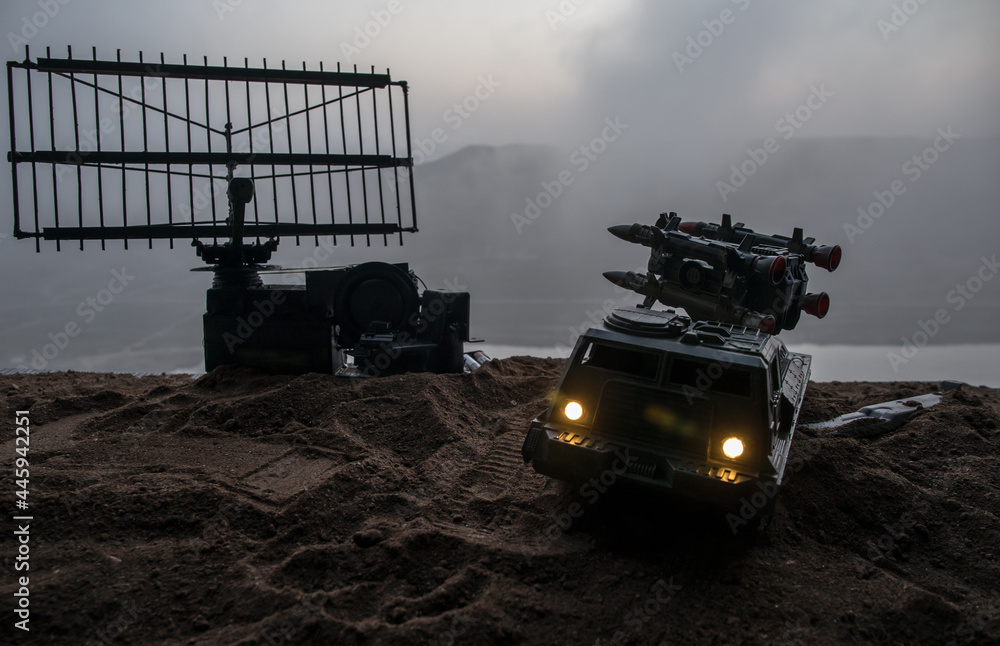 Fototapeta premium Creative artwork decoration. Silhouette of mobile air defence truck with radar antenna during sunset. Satellite dishes or radio antennas against evening sky.