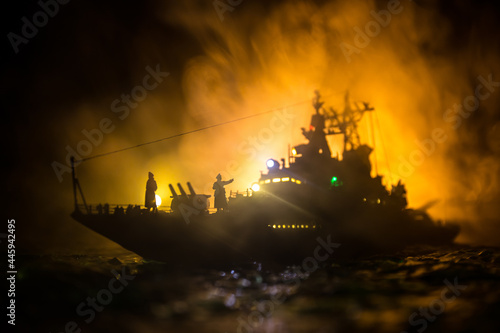 Silhouettes of a crowd standing at blurred military war ship on foggy background. Selective focus.