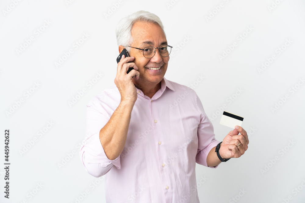 Middle age Brazilian man isolated on white background keeping a conversation with the mobile phone and holding a credit card Middle age Brazilian man isolated on white background keeping a conversation with the mobile phone and holding a credit card
