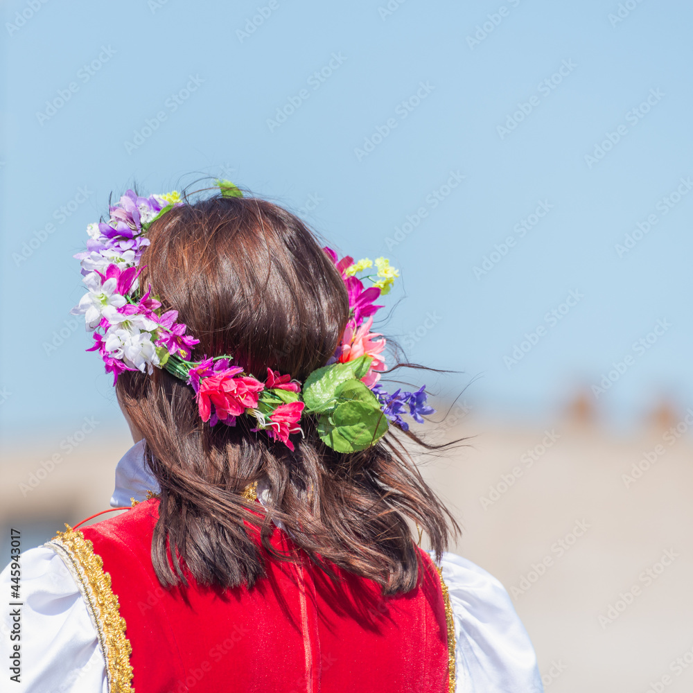 Naklejka premium The girl weaved flowers and a wreath into her hair.