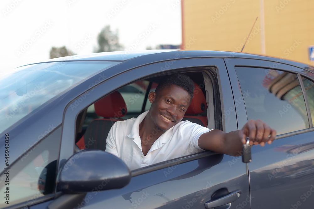 A happy African-American man holds the car keys. Car sales and rentals