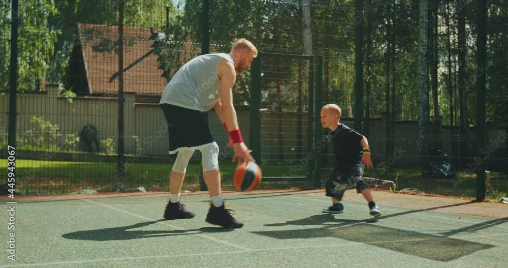 American basketball players athletic instructor and little kid boy in action in basketball court. Dribbling American basketball players athletic instructor and little kid boy in action in basketball court. Dribbling