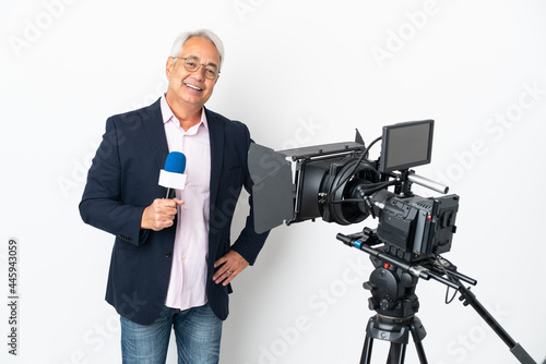 Reporter Middle age Brazilian man holding a microphone and reporting news isolated on white background posing with arms at hip and smiling
