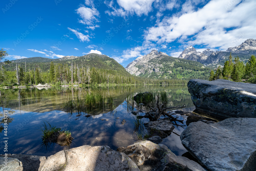 Taggart Lake in Grand Teton National Park, framed by rocks on a sunny calm morning
