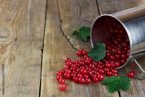 Red currant in a metall mug on wooden background