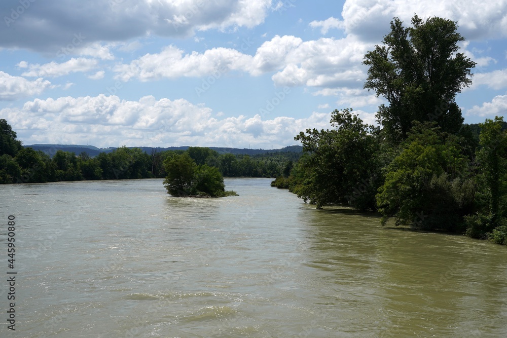 River Rhine on the border between Germany and Switzerland out of banks. High water is caused by heavy rains in July 2021. The river banks and the vegetation are flooded with dirty muddy water. River Rhine on the border between Germany and Switzerland out of banks. High water is caused by heavy rains in July 2021. The river banks and the vegetation are flooded with dirty muddy water.