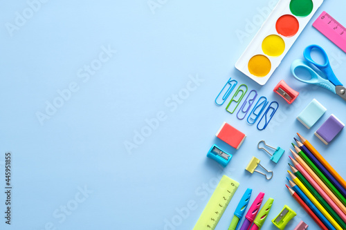 Back to school background with school supplies on blue desk. Flat lay, top view, ovehread.