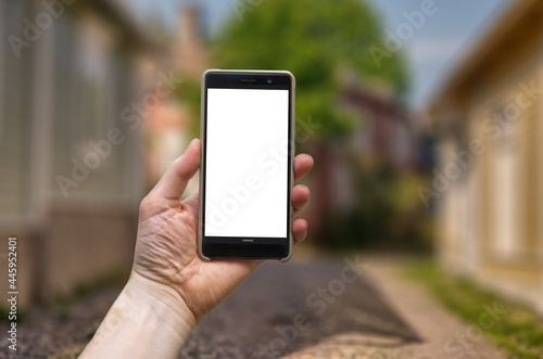Vertical mockup smart phone on man hand with a blurry town street background