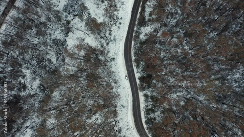 Aerial shot top down cinematic 4k view of white car driving on country road in snow forest at Falls Creek, VIC Australia