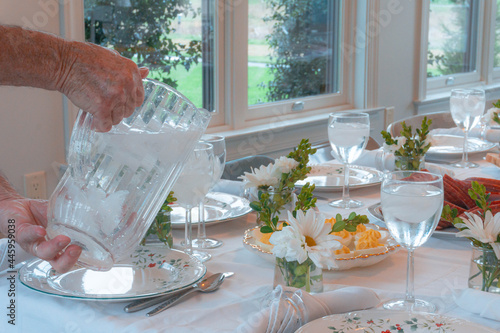 Man Pouring Water at a Table Set for Many People
