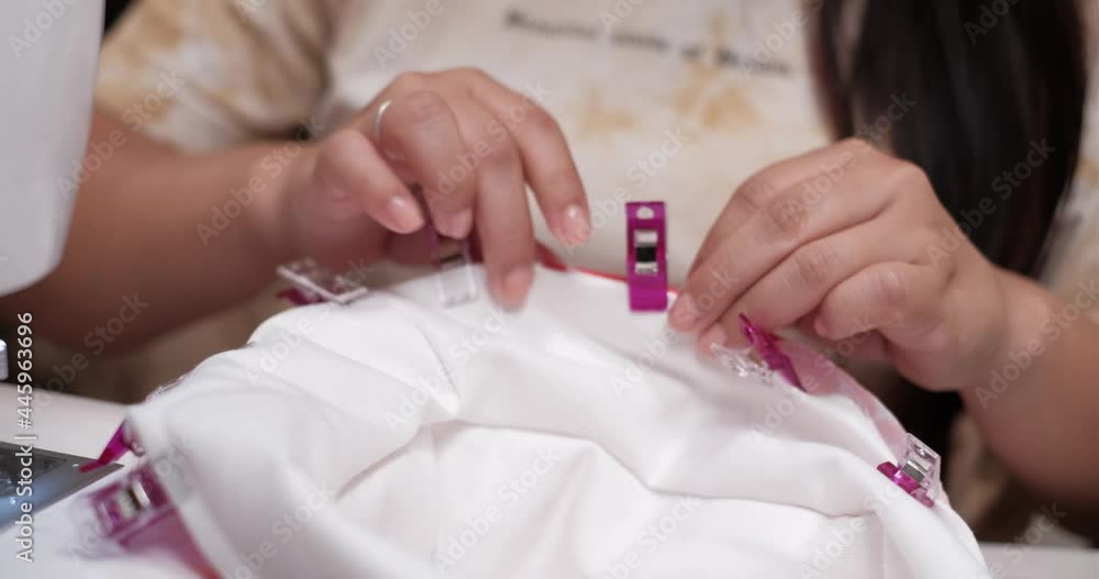 Female adding clips to bucket hat to hold fabrics in place with a sewing machine next to her Female adding clips to bucket hat to hold fabrics in place with a sewing machine next to her