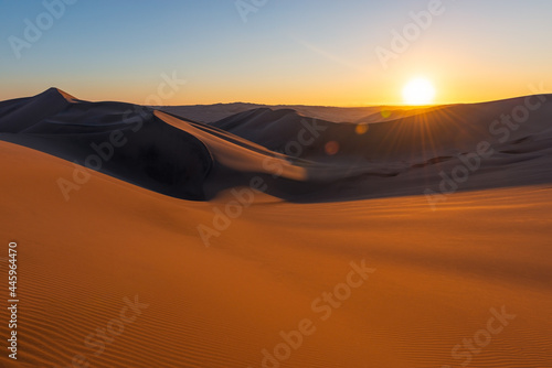 Huacachina desert sunset with lens flare sun star  Peru.