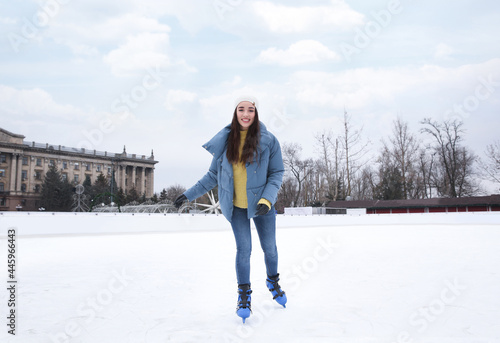 Happy woman skating along ice rink outdoors