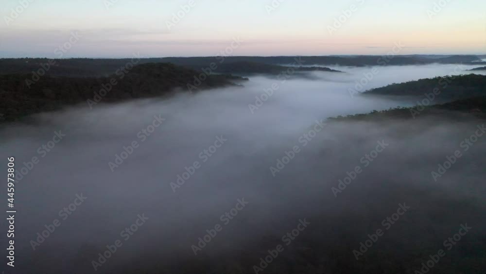 Aerial: A river of white fog blankets the valley below as hill tops stick out like islands, in New South Wales, Australia Aerial: A river of white fog blankets the valley below as hill tops stick out like islands, in New South Wales, Australia