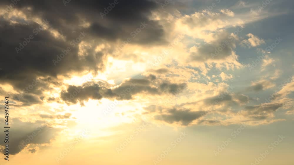 Backlit clouds creating sun rays and slowly morphing and dissipating against a blue sky. Time lapse of weather conditions background wallpaper. Backlit clouds creating sun rays and slowly morphing and dissipating against a blue sky. Time lapse of weather conditions background wallpaper.