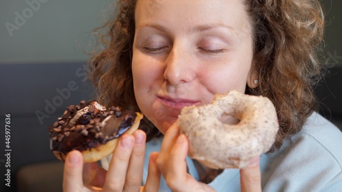 Binge eating concept. Attractive Caucasian woman with eating disorder eating two donuts quickly and at the same time