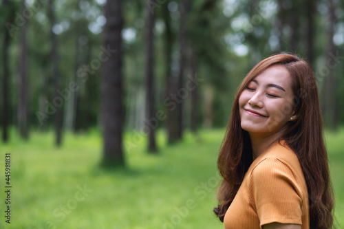 Portrait image of a beautiful young asian woman with eyes closed standing in the park