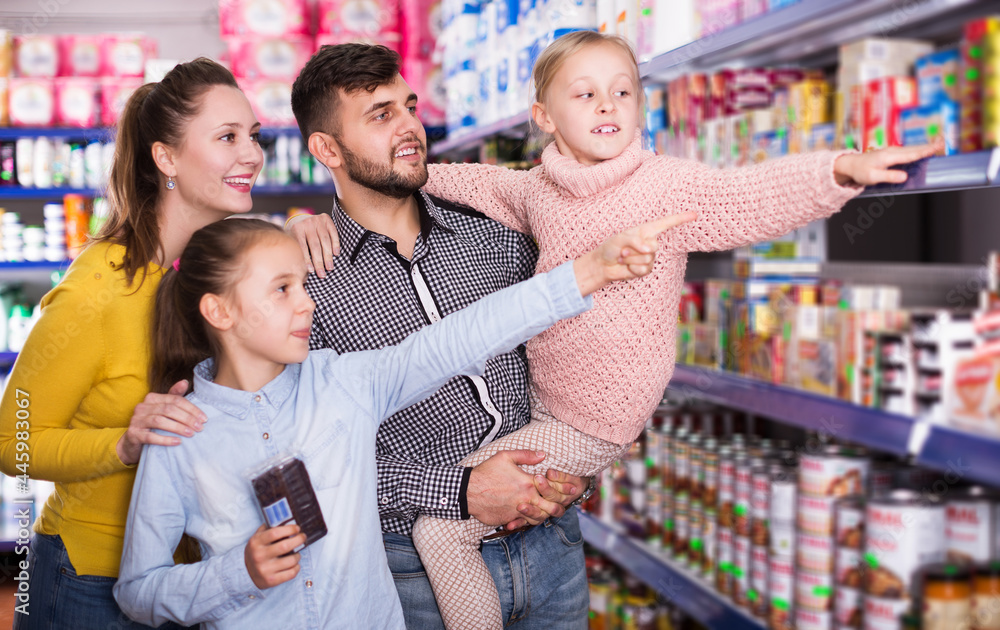 portrait of young glad family of four shopping together in grocery store