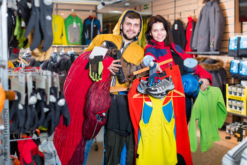 Smiling guy and girl show their choice of sports equipment in the store © JackF