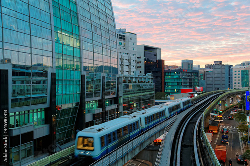 Scenery of a train traveling on elevated rails of Taipei Metro (MRT System ) under dramatic sunset sky with golden clouds reflected on the glass curtain walls of a modern office block in Neihu, Taipei