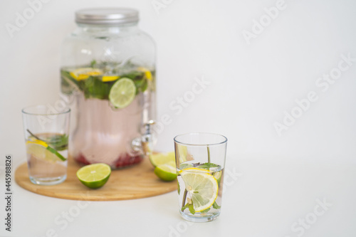 Summer cooling drink with berries and citrus. Lemonade in a reusable glass bottle and glasses. Homemade drink with mint, lime and lemon. Medicinal and healthy drink with vitamin C