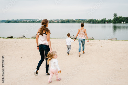 Two mothers with kids walking on nature on summer day. Mom and son, daughter walk on the beach. Concept of happy family. Close Up.