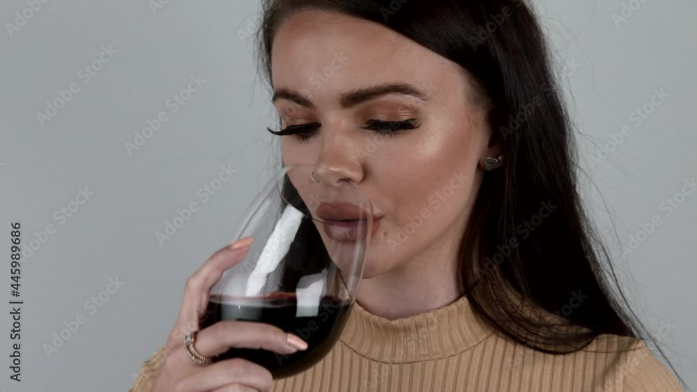 Close Up Of Attractive Female Model With Glass Of Red Wine Drinking. Female Drinks Alcohol. Girl On White Background Drinks Wine. Fashion Beauty Portrait Photoshoot. 4k Slow Motion Video Footage Close Up Of Attractive Female Model With Glass Of Red Wine Drinking. Female Drinks Alcohol. Girl On White Background Drinks Wine. Fashion Beauty Portrait Photoshoot. 4k Slow Motion Video Footage
