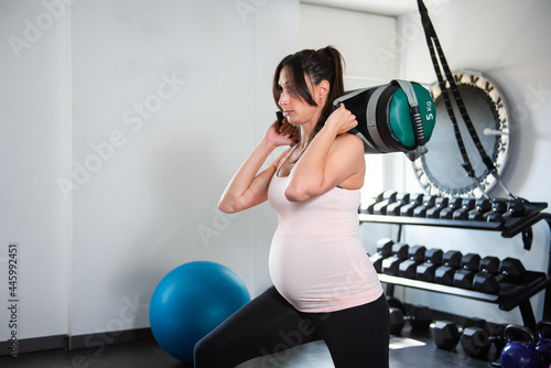 Canvas Print pregnant woman doing squat with weight in gym