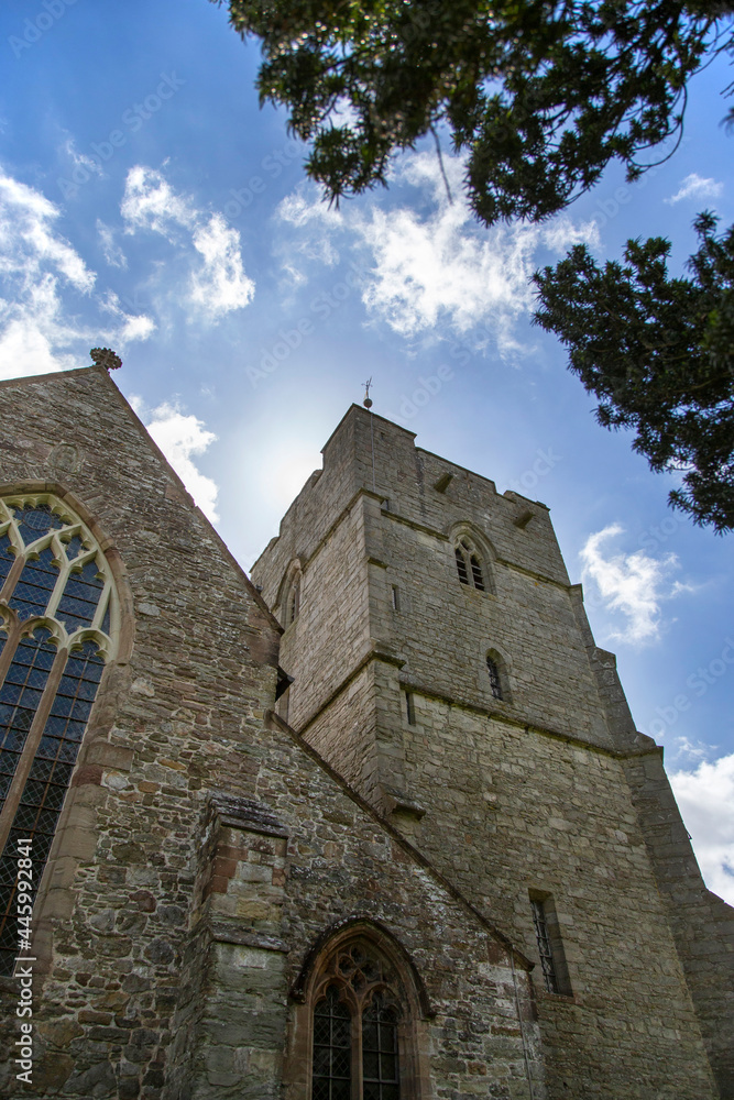 Presteigne church window, tower and yew tree in Powys, Wales.  With a blue sky background