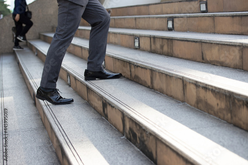 Business and grow up concept. Close up legs business man holding briefcase and walking up stairs going to work at morning in the city.