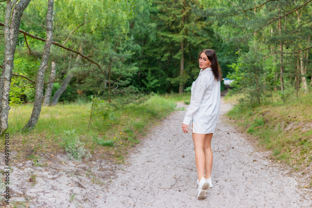 Young pretty woman walking in a forest, sunny summer day,freedom.Summertime and lifestyle.Back view. Young pretty woman walking in a forest, sunny summer day,freedom.Summertime and lifestyle.Back view.