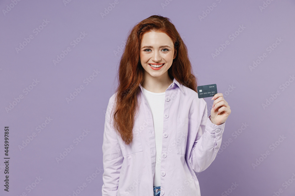 Smiling beautiful charming fun young redhead curly green-eyed woman 20s wears white T-shirt violet jacket hold in hand credit bank card isolated on pastel purple color wall background studio portrait Smiling beautiful charming fun young redhead curly green-eyed woman 20s wears white T-shirt violet jacket hold in hand credit bank card isolated on pastel purple color wall background studio portrait