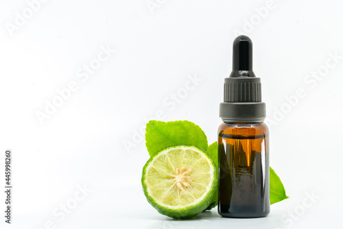 Beautiful packshot of Bergamot essential oil in a small glass bottle with fresh bergamot fruit with green leaf on white background. Blank space on the bottle for label design branding.
