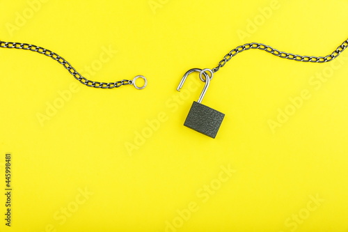 unlocked padlock with chain on yellow background with copy space photo