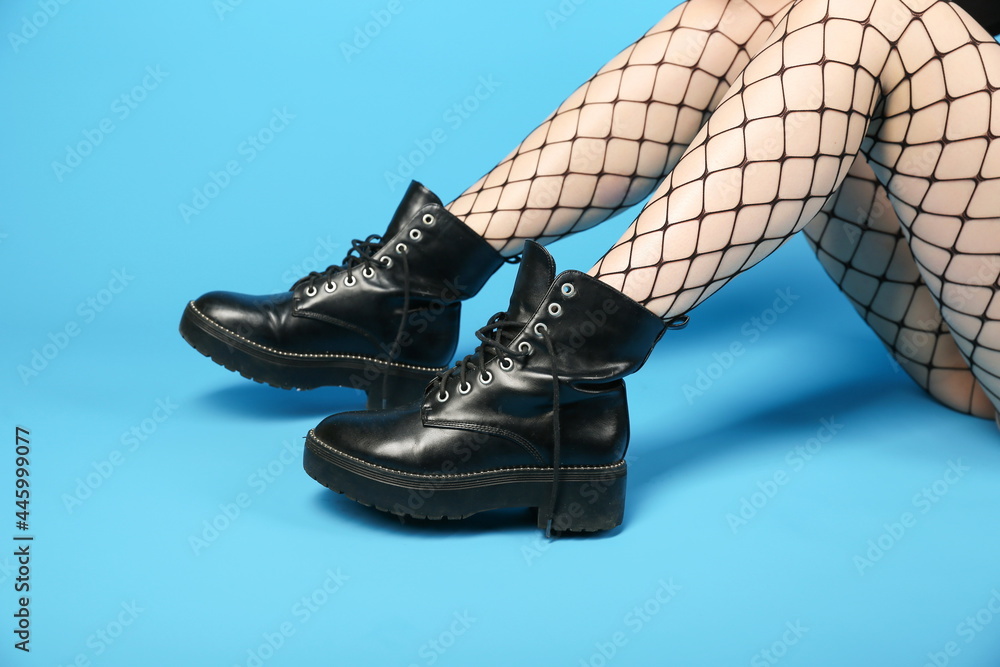 woman legs wearing fishnet pantyhose and combat boots on blue background  Photos | Adobe Stock