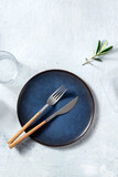 Blue ceramic plate, shot from the above with cutlery and an olive branch, Mediterranean cuisine concept with copy space, a flat lay