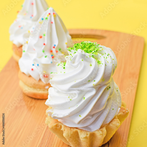 Sponge cake with protein cream on a wooden kitchen board. Delicious sweet food concept. Top and side view. Focus on the foreground. Blurred background.