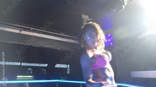 Close-up of a girl in underwear dancing to the beat of the music with her hands. She is dressed in pink underwear and is surrounded by club floodlights. photo