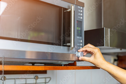 Woman setting timer for cooking food in microwave.