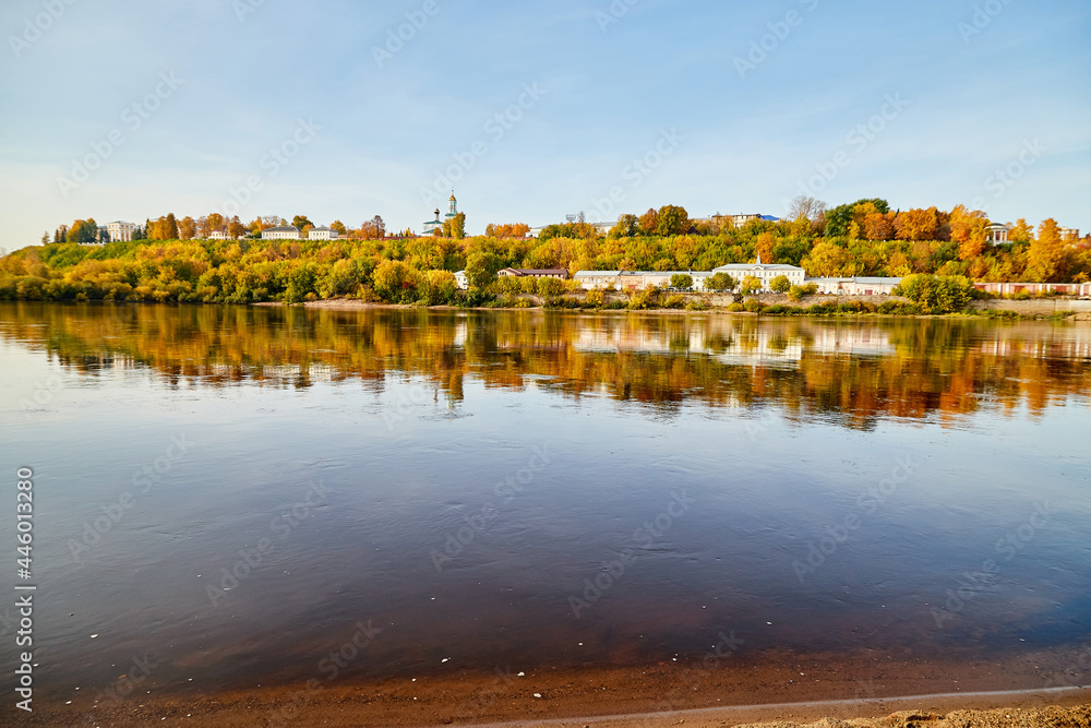 Natural view of the landscape with a lake or river and a city on the other side on the yellow shore in autumn day with blue sky