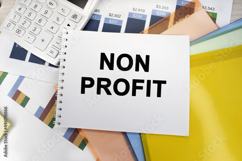 On the financial document near the white calculator there is a notebook on which it is written a non-profit organization. Business and financial concept