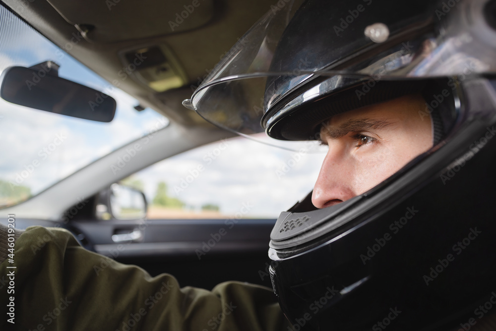 Rally racer in the helmet sits by the car steering wheel concept. Rally racer in the helmet sits by the car steering wheel concept.