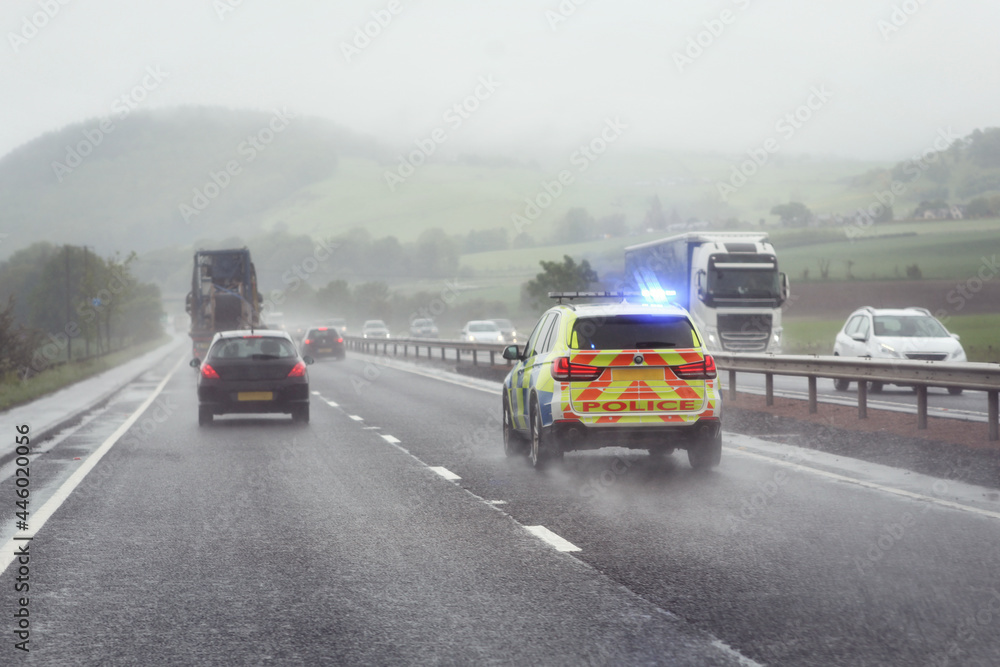 Police siren flashing blue lights on motorway in bad weather conditions