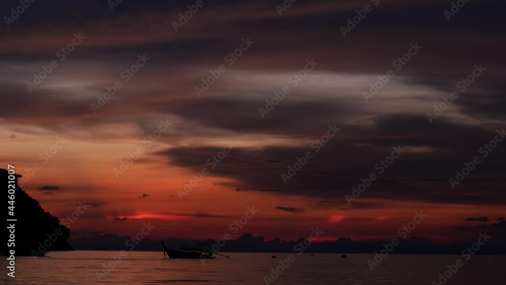 Gloaming sky after sunset, red colored sky at horizon, dark clouds slide on. Time lapse shot of nightfall time at tropical island, sea bay view, few boats stay on water Gloaming sky after sunset, red colored sky at horizon, dark clouds slide on. Time lapse shot of nightfall time at tropical island, sea bay view, few boats stay on water