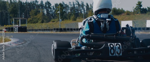 Fotografía Back view of teenager professional racer driving his go kart on a race track
