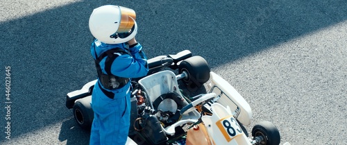 Teenager professional karting racer putting on protective gear on a race track