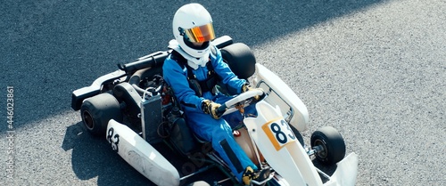 Teenager professional karting racer sits inside his go kart on a race track
