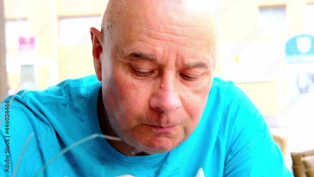 elderly positive man in a blue t-shirt close-up eating asian food in a street cafe in the summer, bright light of the sun concept of vacation, tourist travel, summer vacation, summermood elderly positive man in a blue t-shirt close-up eating asian food in a street cafe in the summer, bright light of the sun concept of vacation, tourist travel, summer vacation, summermood